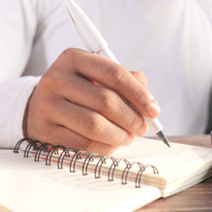 Man-writing-in-notebook-with-pen-to-illustrate-branded-promotional-merchandise