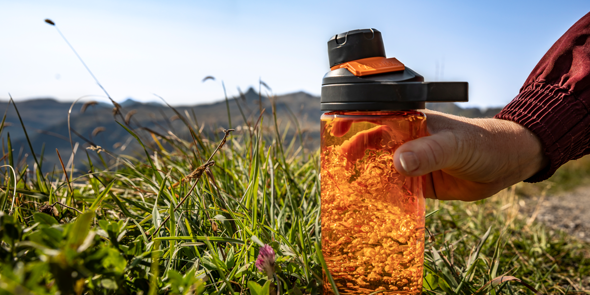 Person-outdoors-picking-up-Camelbak-bottle-that-uses-Tritan-Renew-technology